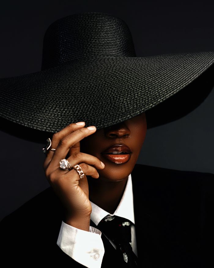Stylish portrait of a woman in a black outfit and large hat, capturing elegance in Abuja.