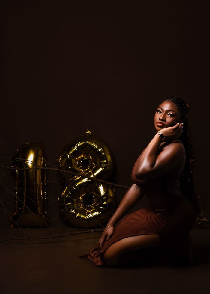 Elegant woman posing with golden balloons celebrating her 18th birthday.